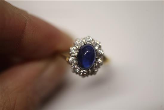 A cabochon sapphire and diamond cluster ring, size N.